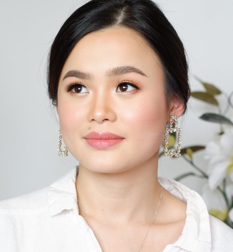 Soft bridal makeup with a rosy lip, hair swept back, in a white shirt